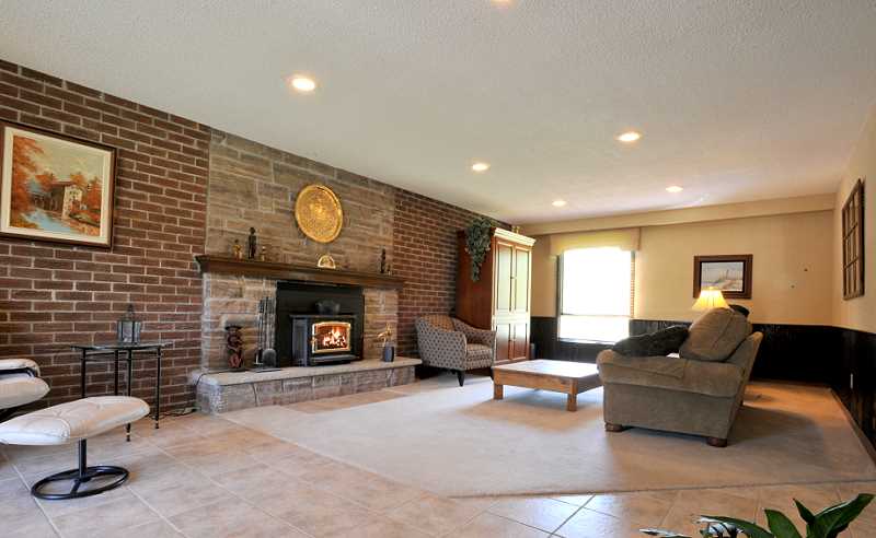 Family room has a combination of new ceramic and broadloom, a wood-burning insert, pot lighting, wainscoting and walk-out to the deck and pool area