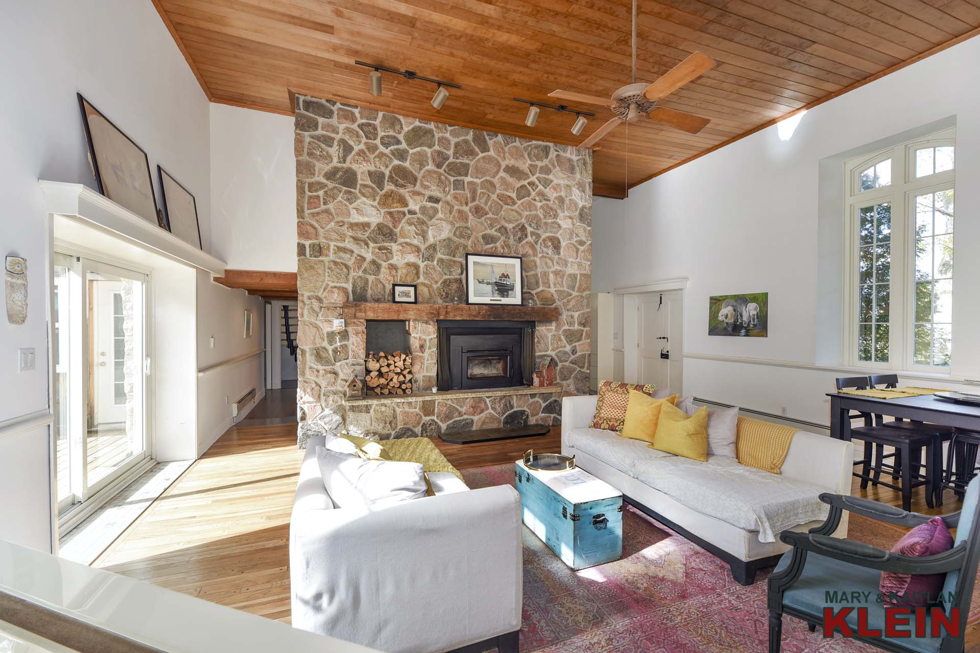 floor-to-ceiling stone wood burning fireplace with wooden mantel